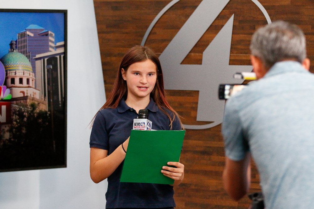 A girl pretends to do a news report
