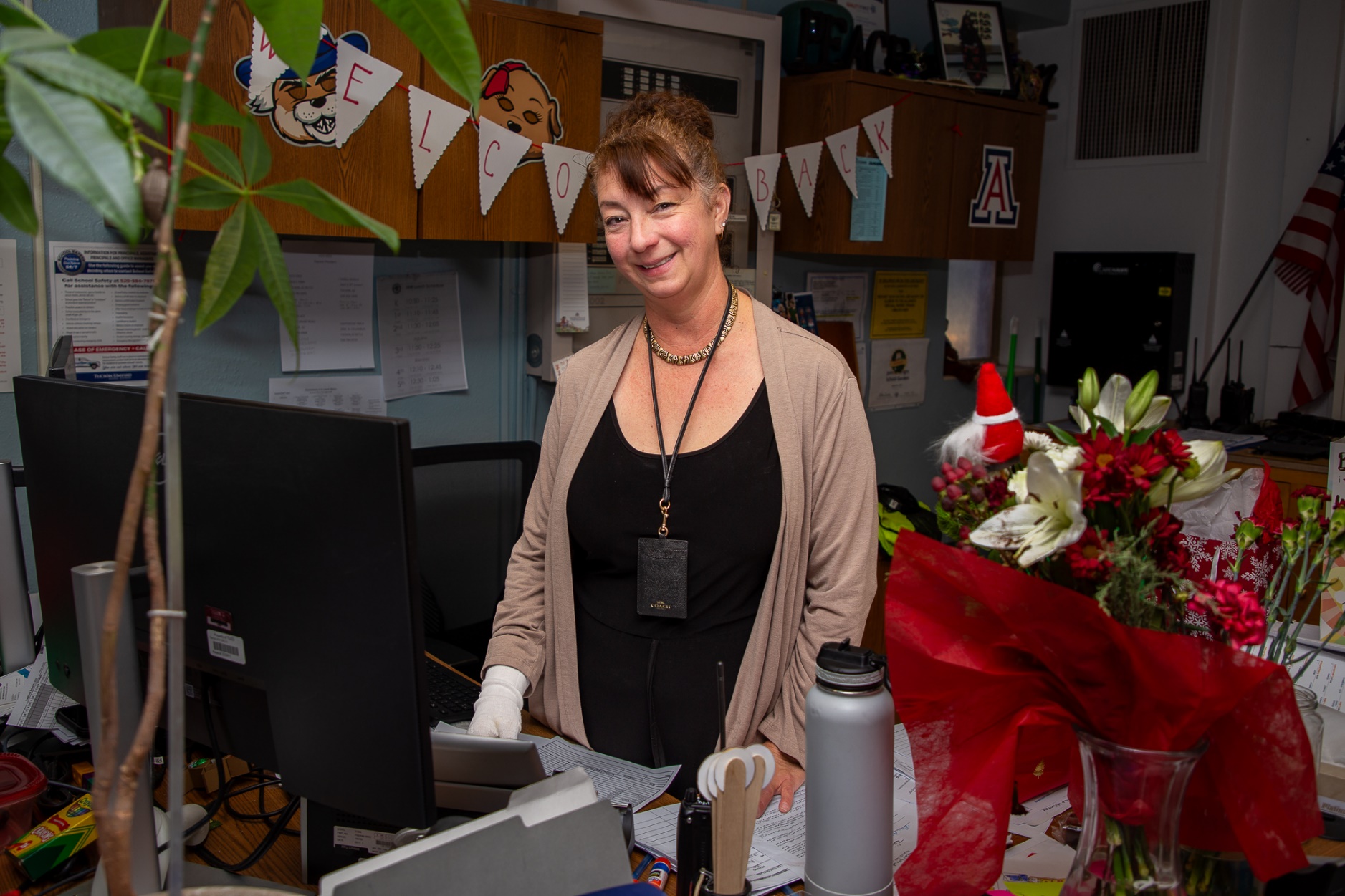 A woman stands behind her desk