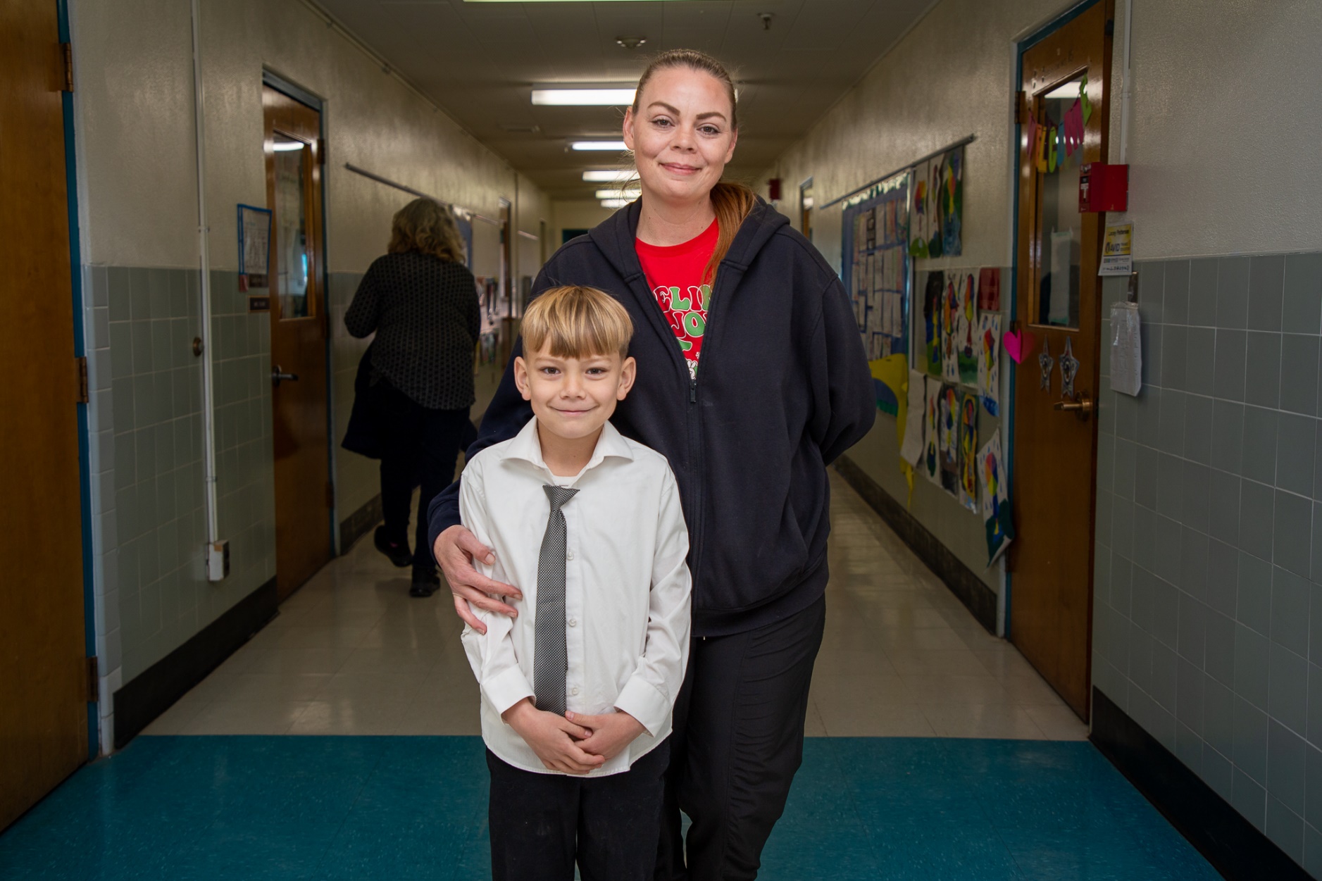 A woman stands in the hallway with her young son