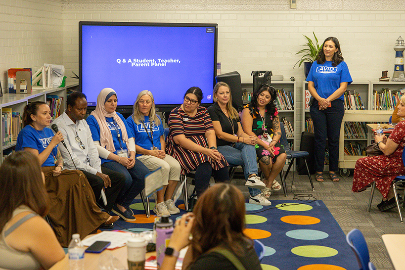A group of people sitting in a row of chairs in front of a blue screen