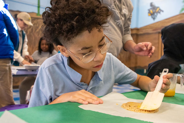 Child carefully brushes butter to coat the empanada