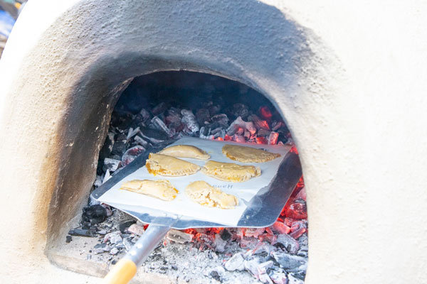 Finally, empanadas are held over hot coals in a ceramic oven to cook