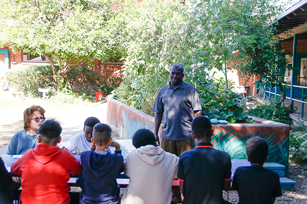 A man talks to students in the school courtyard