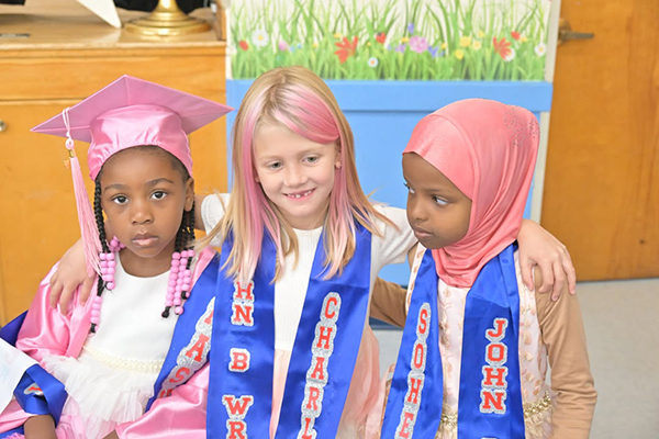 Three girls sit together wearing their grad sashes